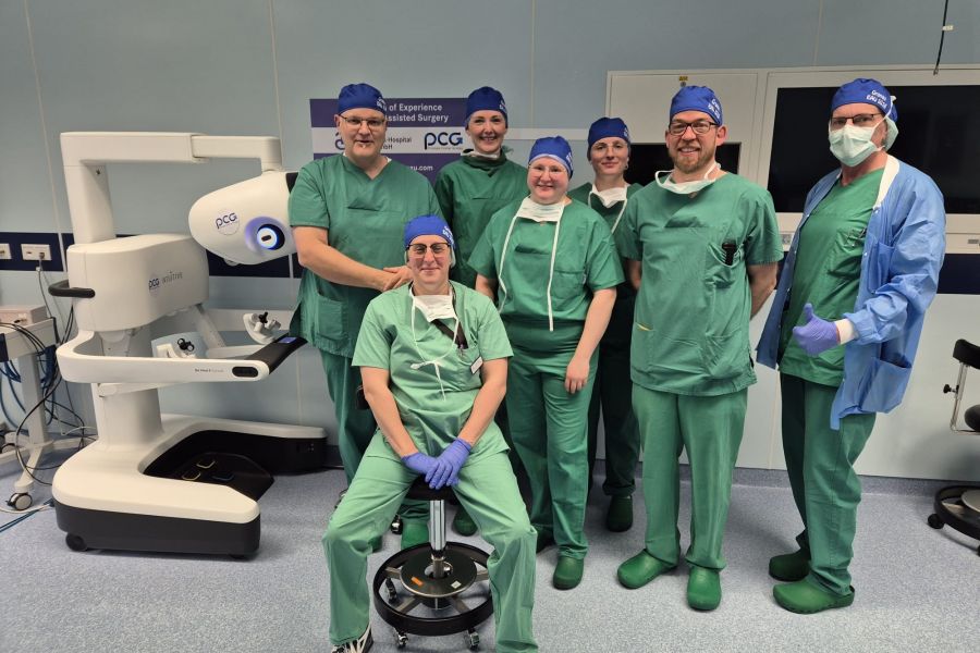 Das siebenköpfige Team für die Live-OP der Prostatektomie stehend neben der Konsole des da Vinci 5 Operationssystems 