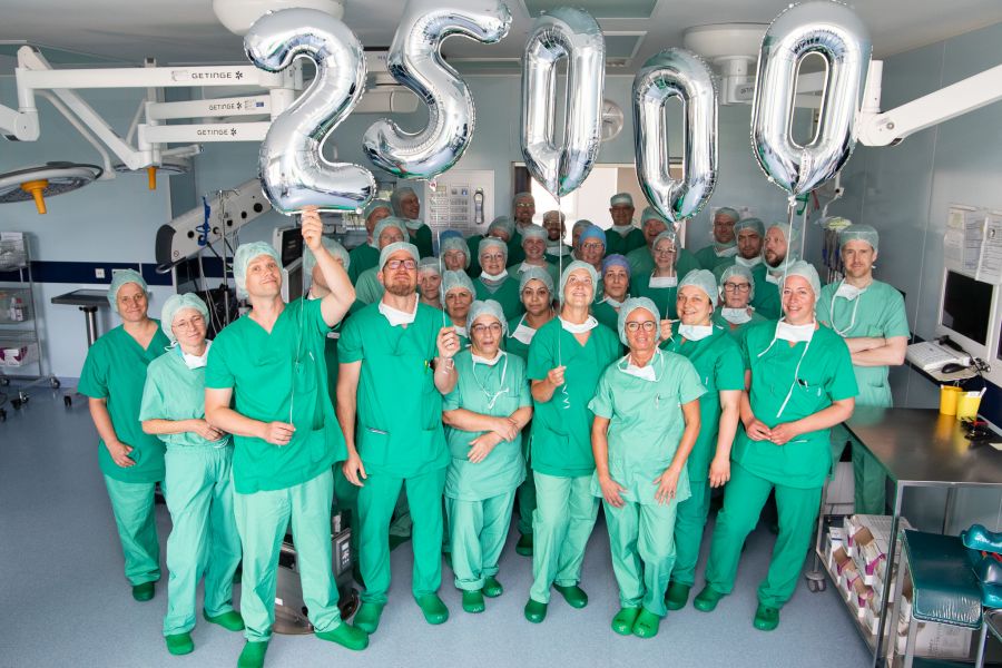 Ein Großteil des OP-Teams im Operationssaal mit dem da Vinci 5 und einer aufblasbaren 25.000. 